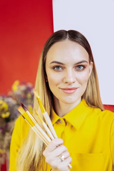Art teacher holding brushes before teaching her students