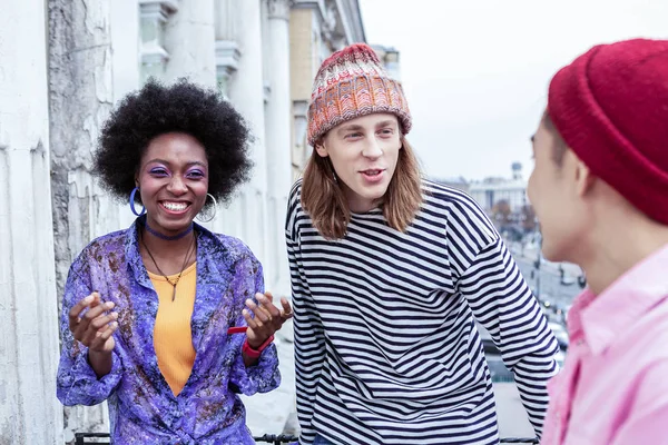 Кучерява темноволоса жінка в масивних сережках розмовляє з друзями — стокове фото