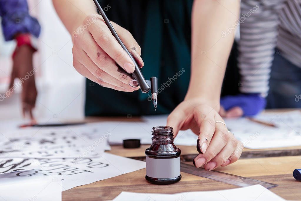 Female artist with natural nail art practicing drawing with pen and ink