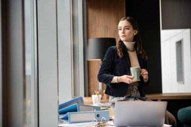 Esmer kız iki elle bardakta tutan konsantre