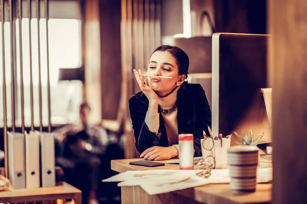 Cheerful young female person playing with pencil — Stock Photo, Image