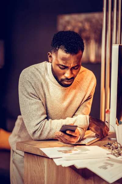 Sério macho de pele escura usando seu gadget moderno — Fotografia de Stock