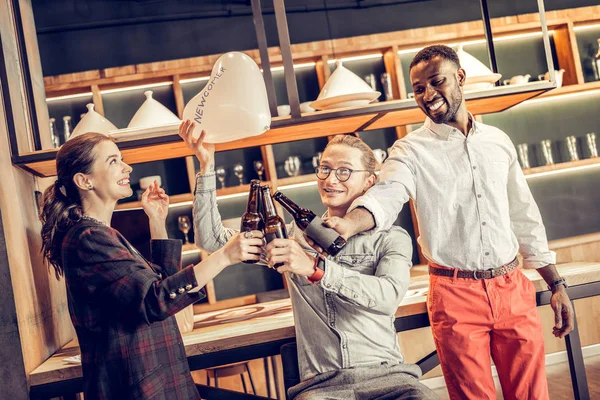 Joyful male person touching bottles with partners — Stock Photo, Image