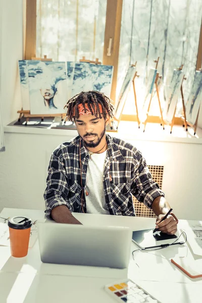 Молодий творчий художник п'є каву і працює на ноутбуці — стокове фото