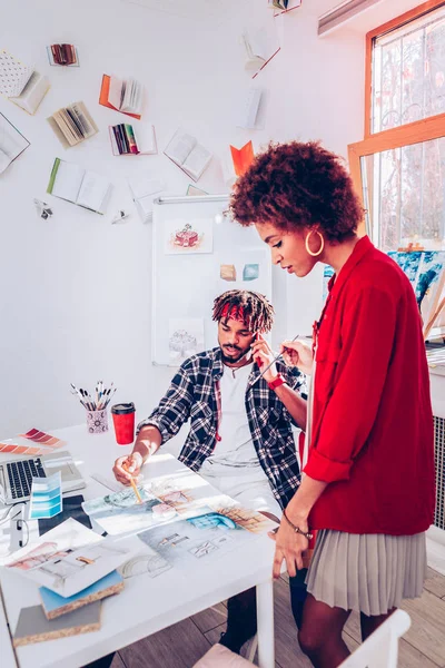 Κομψό σχεδιαστής φορώντας κόκκινο σακάκι στέκεται κοντά τον συνάδελφό της — Φωτογραφία Αρχείου