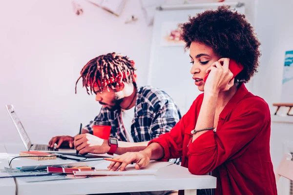 Diseñador de pelo oscuro rizado con bonita pulsera que habla por teléfono — Foto de Stock