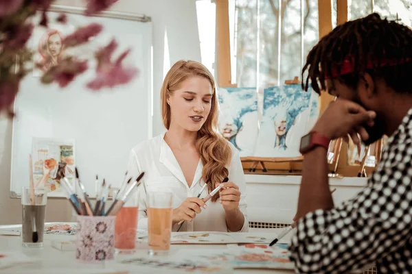 Rubia artista de pelo recomendando buen pincel de pintura a su colega — Foto de Stock