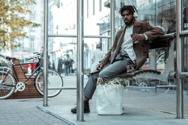 Çok yorgun. Kağıt bardak tutan ve onun taşıma için bekleyen memnun sakallı erkek kişi