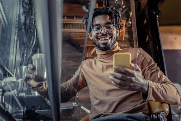 Positieve blij brunette man kijken naar zijn gadget — Stockfoto