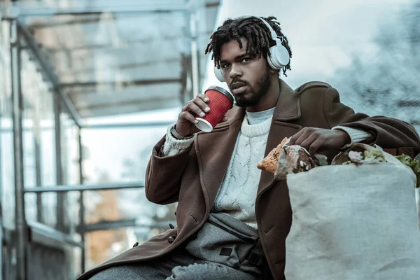 Hombre barbudo concentrado bebiendo café caliente en la estación — Foto de Stock