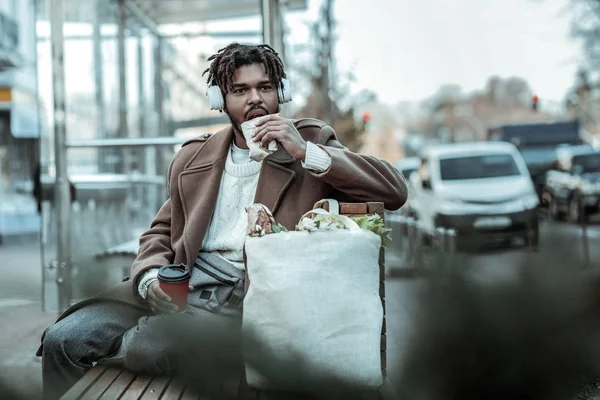 Homme brunette affamé mangeant de la pâtisserie près de la gare — Photo