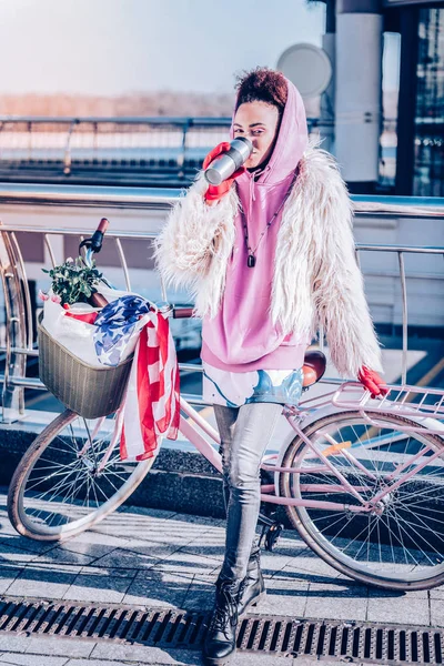 Concentrada chica elegante apoyada en su bicicleta —  Fotos de Stock