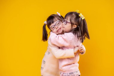 Charming positive sisters with chromosome abnormality hugging each other clipart