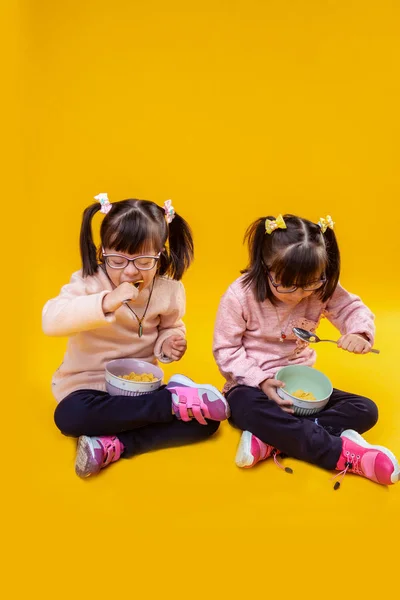 Focused little girls with mental disorder eating cereals with milk — Stock Photo, Image