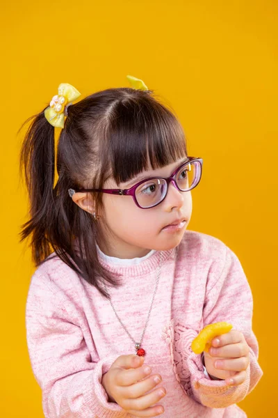 Dark-haired girl with down syndrome carrying orange chips — Stock Photo, Image