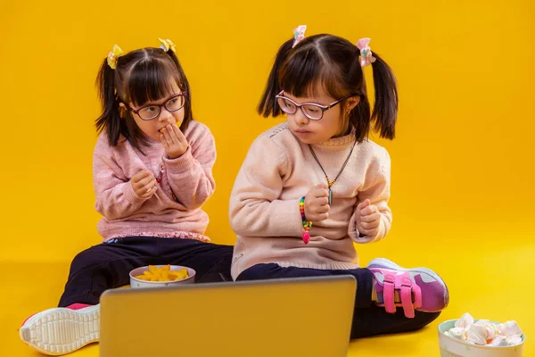 Dark-haired pretty sisters with mental disorder sitting against laptop — Stock Photo, Image