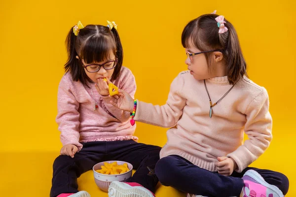 Agradable chica morena proponiendo patatas fritas a su hermana —  Fotos de Stock