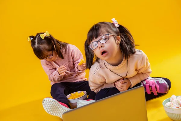 Cute girl with two tails looking in camera while her sister sitting behind — Stock Photo, Image