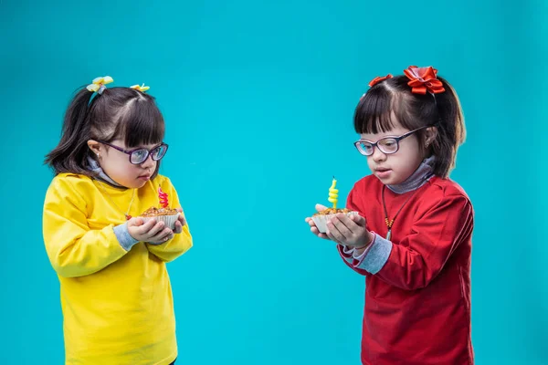 Cute little sisters wearing colorful outfits and carrying cupcakes — Stock Photo, Image