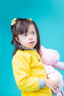 Pembe oyuncak sarılma. Kısa saçlı meraklı çocuk oyuncak kolu altında duran büyük kahverengi gözleri ile