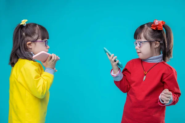 Two twin sisters with down syndrome carrying mobile phones — Stock Photo, Image