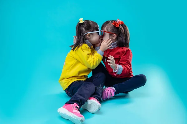 Two twin sisters with genetic disorder playing together on bare floor