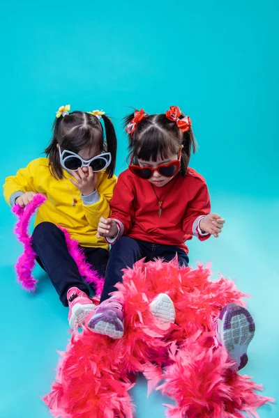 Hermanitas gemelas que tienen estado de ánimo de vacaciones mientras juegan con boa rosa — Foto de Stock