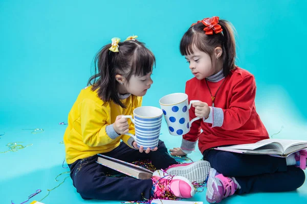 Carefree little sisters with mental disorder clinking giant cups — Stock Photo, Image