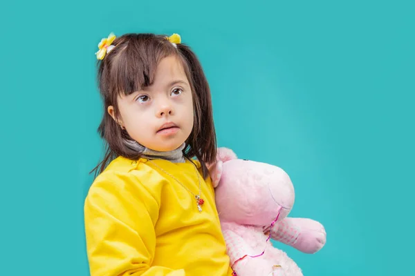 Niño Atento Niña Morena Con Síndrome Abrazando Juguete Rosa Mientras —  Fotos de Stock