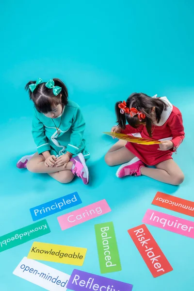 Girls with hair tails attentively reading words on colorful nameplates — Stock Photo, Image