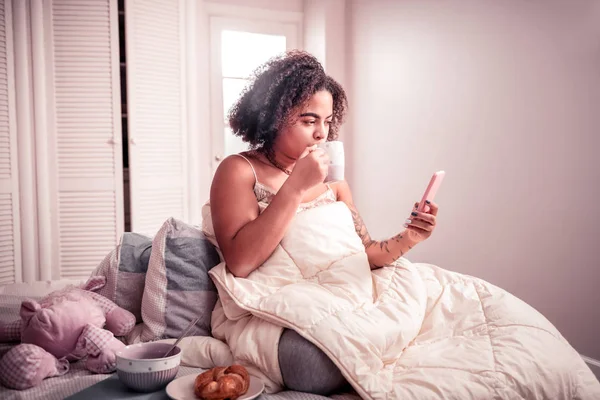 Attentive short-haired woman texting massages on her smartphone