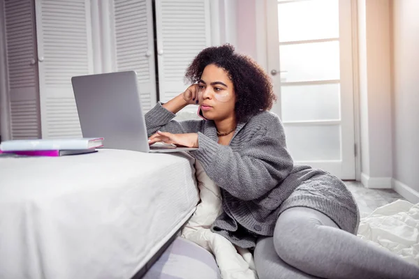 Femme bouclée attentive portant un tissu confortable et attachant sur le clavier de l'ordinateur portable — Photo