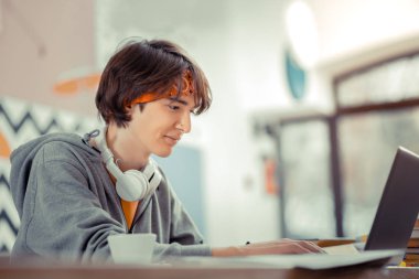 Kafede otururken bilgisayarla çalışan genç