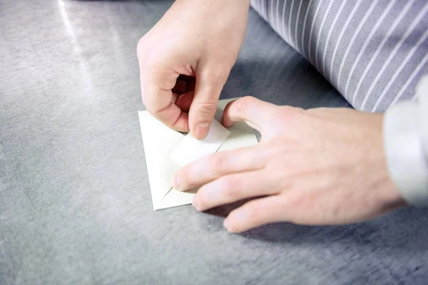 Закрыть руки мужчин, которые прячут бумагу в конверт — стоковое фото