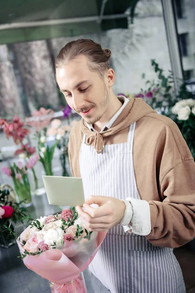 Jovem florista atencioso que trabalha na boutique sozinho — Fotografia de Stock