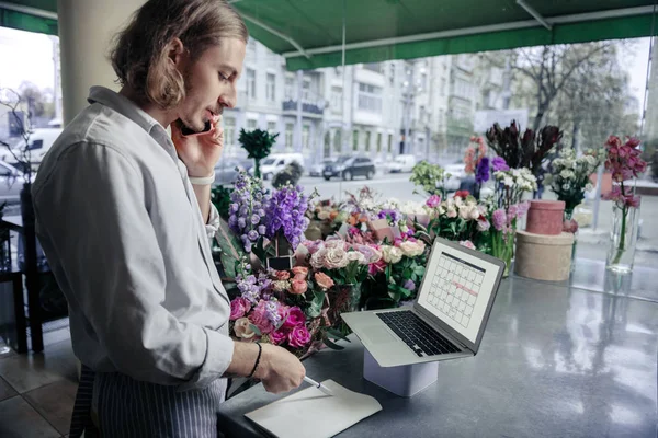 Serious shop assistant talking per telephone with partner — Stock Photo, Image