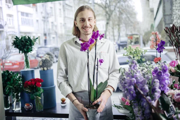 Positive delighted blonde male person selling orchid — Stock Photo, Image