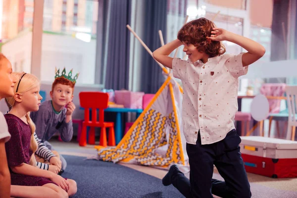 Spielerisches lockiges Kind, das während des Spiels Gesichter macht — Stockfoto