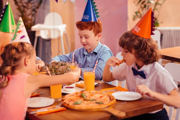 Hungry brunette boy eating cheese stick in cafe — Stock Photo, Image