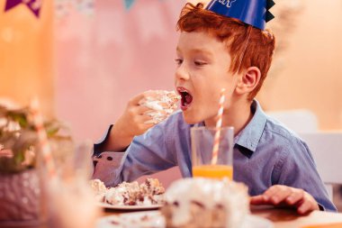 Aç kızıl saçlı çocuk lezzetli doğum günü pastası yiyor
