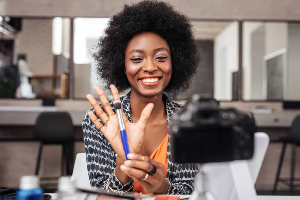 Prachtige Afrikaanse Amerikaanse vrouw met felle lippenstift testen van een nieuwe concealer — Stockfoto