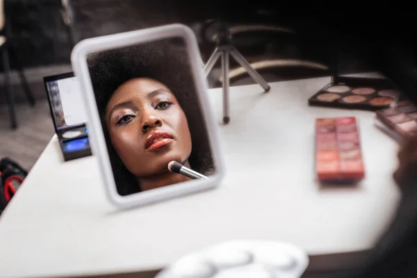 Śliczny african american kobieta z kręconymi włosami robi makijaż — Zdjęcie stockowe