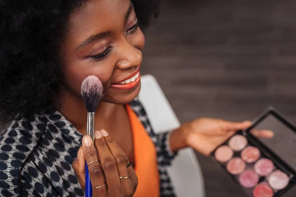 Smiling dark-skinned woman with curly hair feeling gorgeous