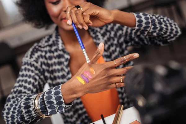 Låter prova. Vackra mörkhyade afroamerikanska kvinna bär ett guldarmband som sätter nya färgrutor på hennes hand — Stockfoto