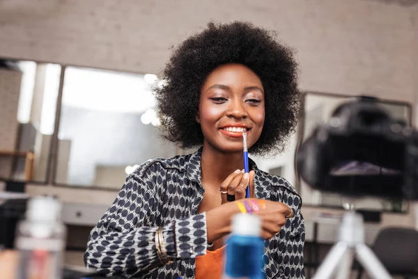 Incredibile donna africana americana con i capelli ricci cercando su un nuovo labbro liquido — Foto Stock