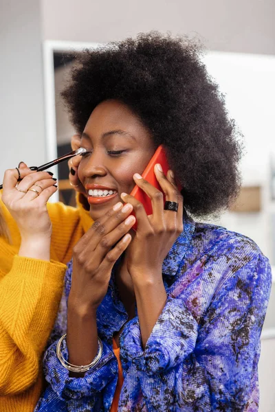 Estilista en un suéter amarillo grueso poniendo sombras en los párpados modelos — Foto de Stock