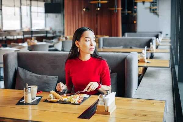 Vrouw zitten op grijs sofa in restaurant genieten van haar lunch — Stockfoto