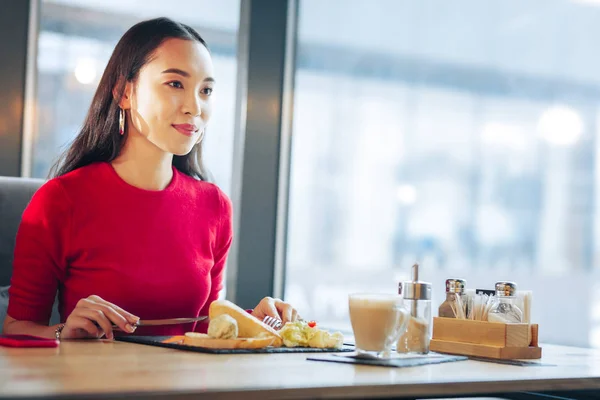 Женщина чувствует облегчение, наслаждаясь завтраком в кафетерии — стоковое фото