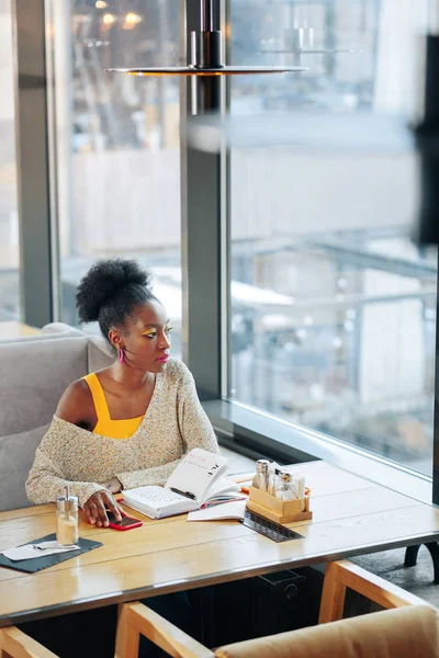 Mujer rizada afroamericana sentada cerca de una gran ventana — Foto de Stock