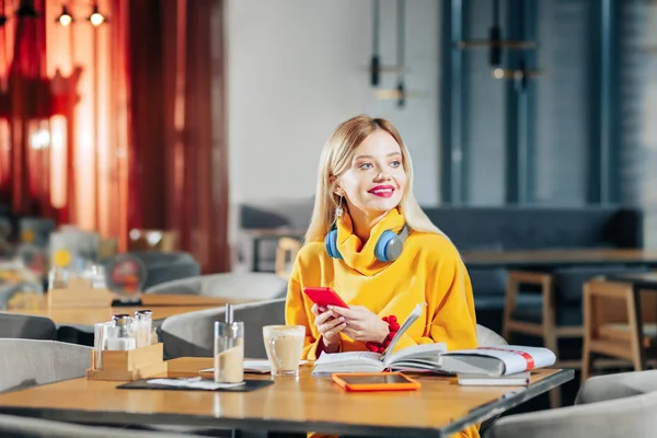 Joven freelancer rubia sosteniendo su smartphone rojo —  Fotos de Stock